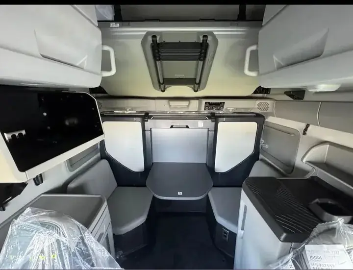 Sleeper truck cabin with seating, a table and overhead storage